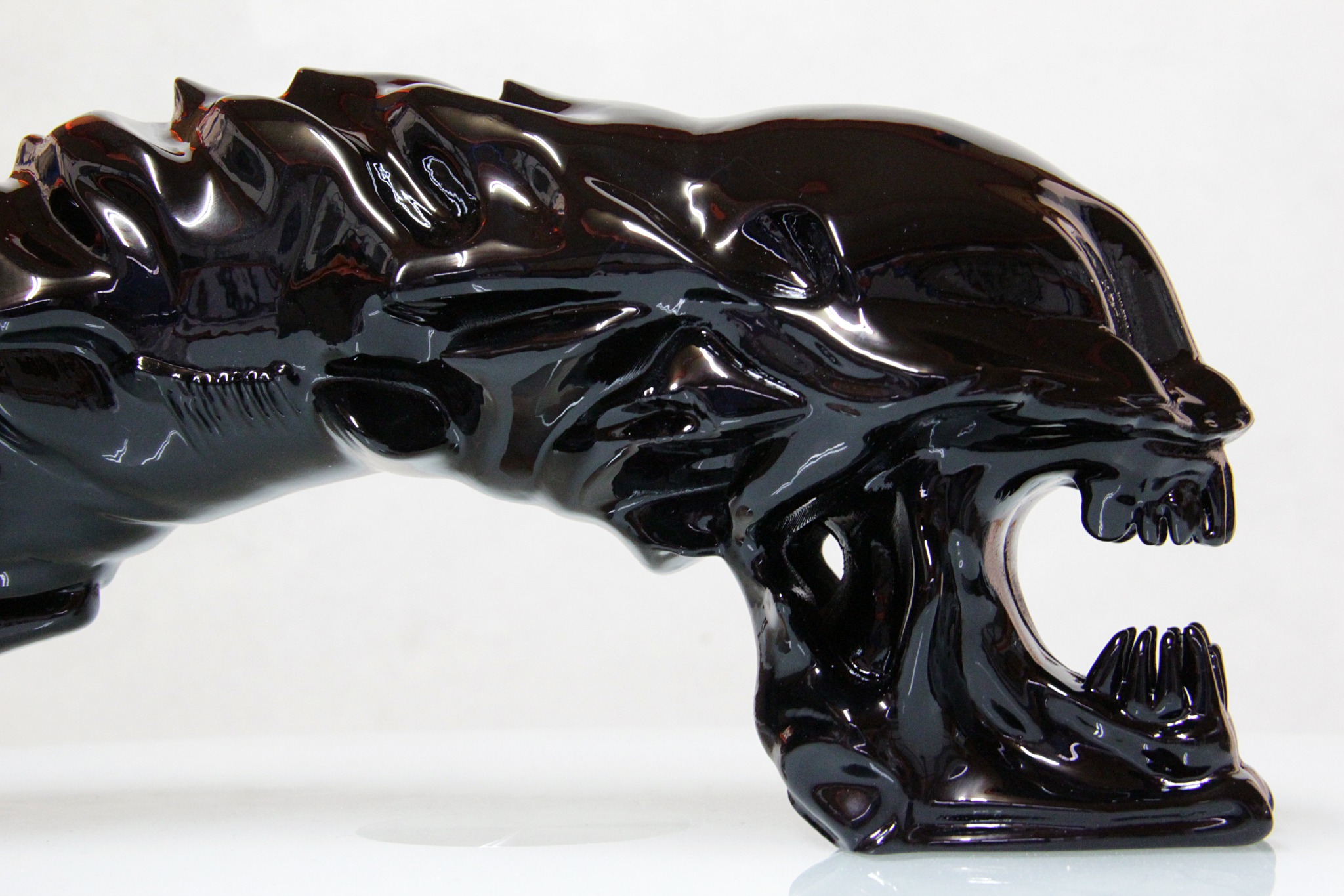 Vista lateral de una escultura Alien negra con acabado brillante